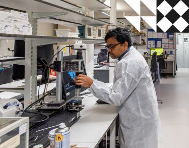 Male student in a lab coat setting up digital microscopeMale student in a lab coat setting up digital microscope.