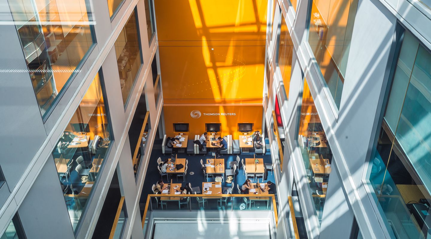 Looking down the sunlit central atrium of Bunhill Row, with a study space at it's base.