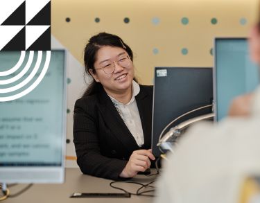Female student smiling in front of a computer