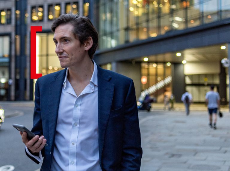 Person standing in front of a building with a phone in his hand