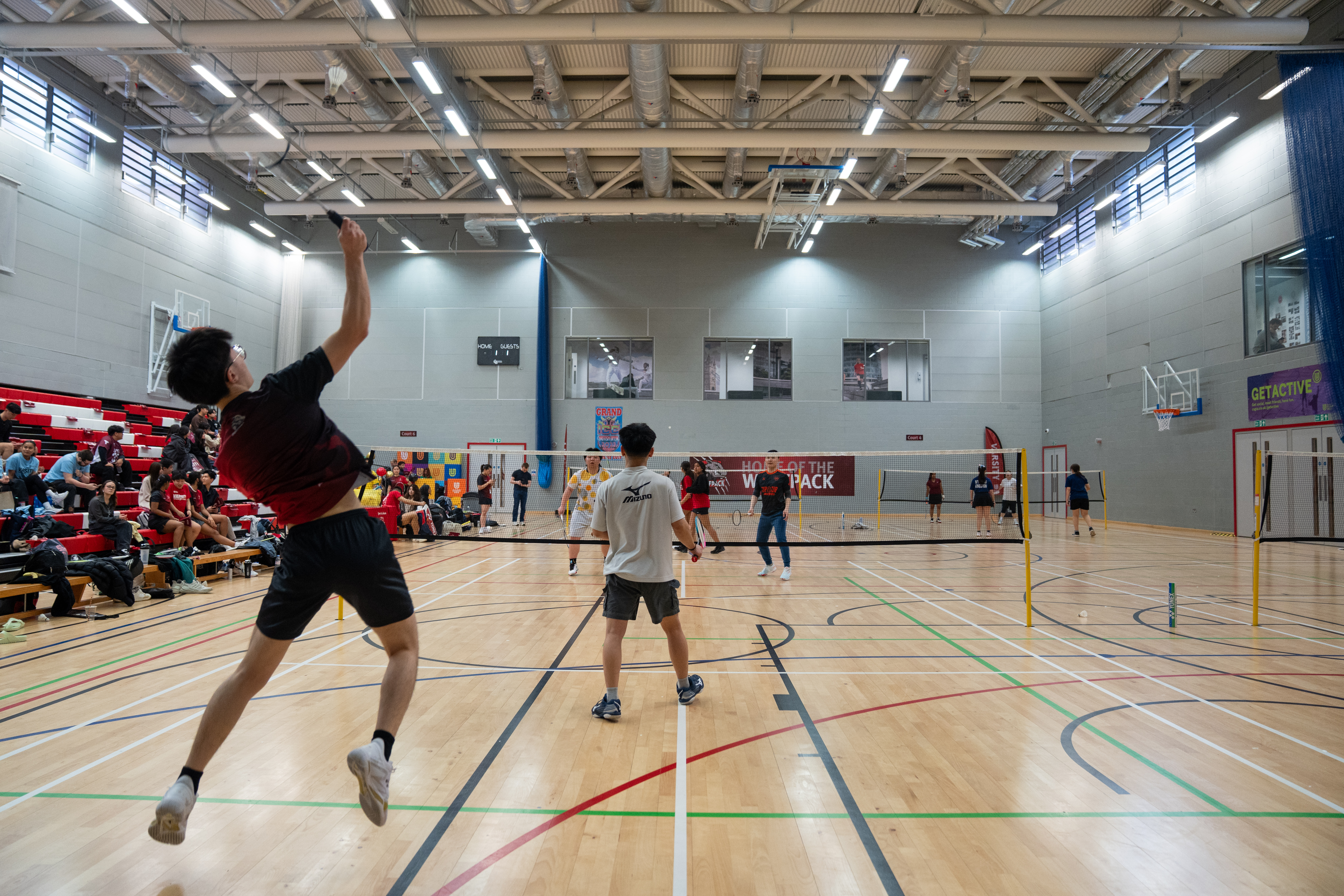 Photo of a badminton court with a person jumping to hit the shuttlecock