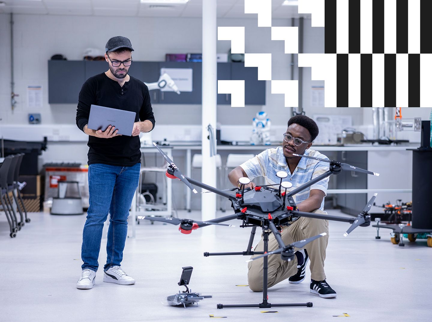 Two students, one with a laptop and the other working on a device