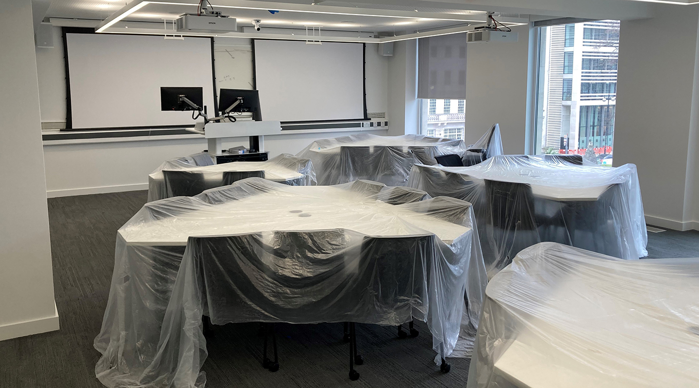 Classroom with brand new triangular desks still covered in dustsheets.
