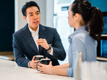 Two smartly dressed Bayes students engaged in conversation over a coffee.