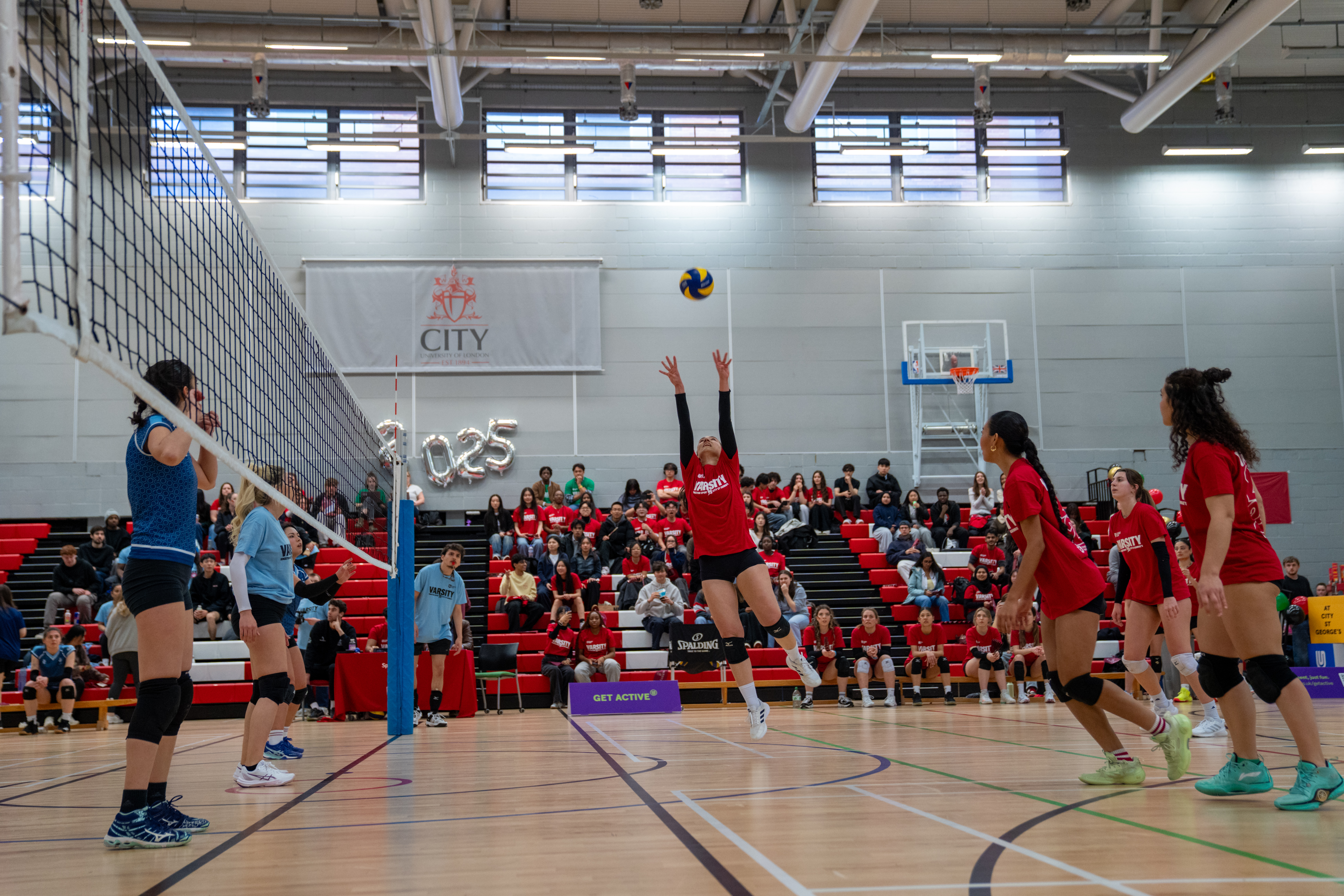 Woman jumping to hit a volleyball over a net