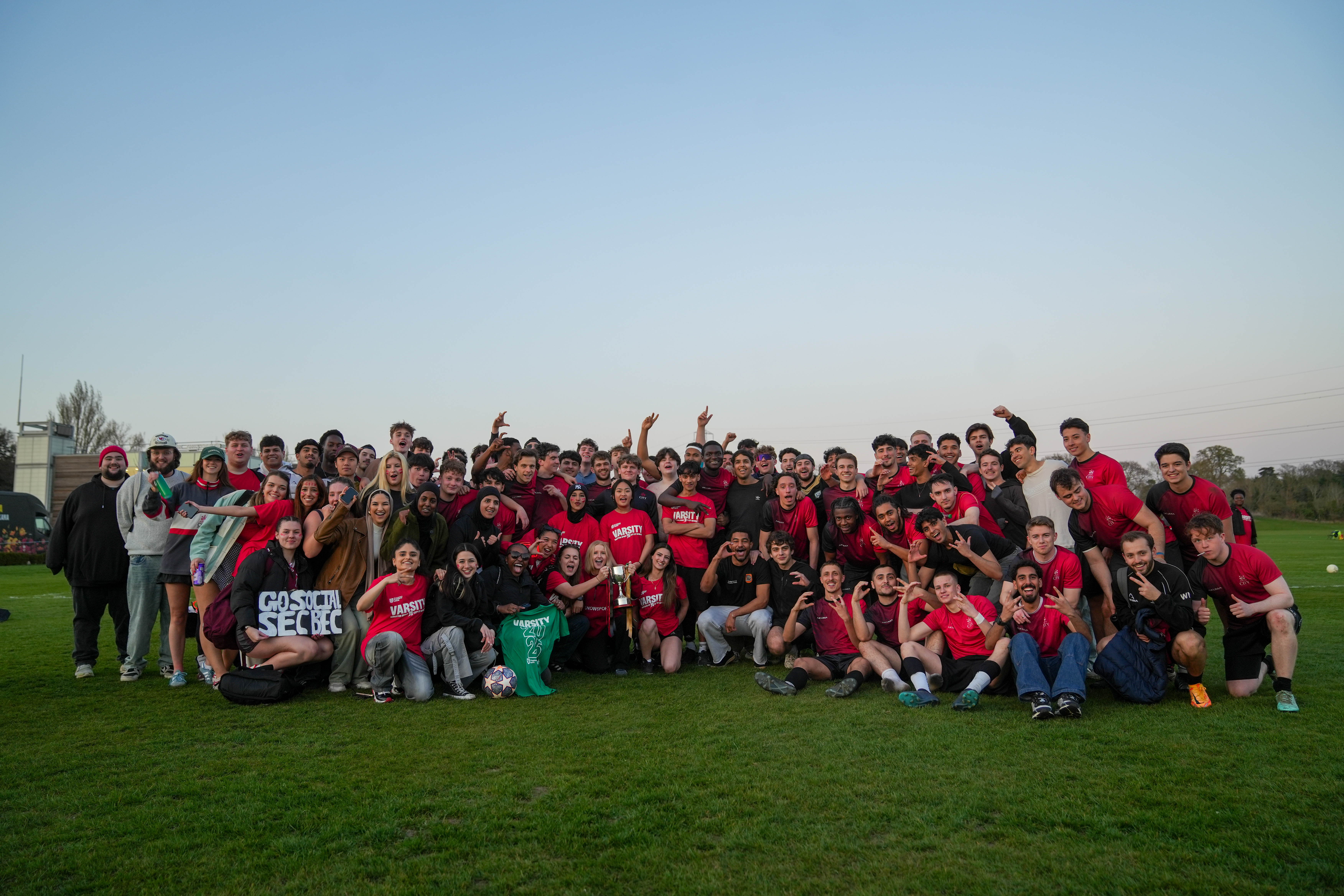 A group of students on a playing field holding a trophy