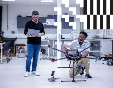 Two students, one with a laptop and the other working on a device