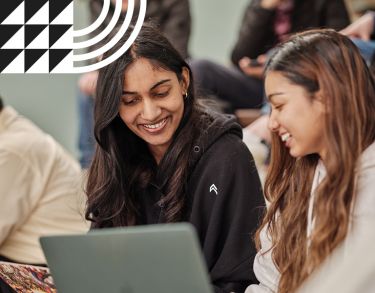 Two female students smiling in a lecture