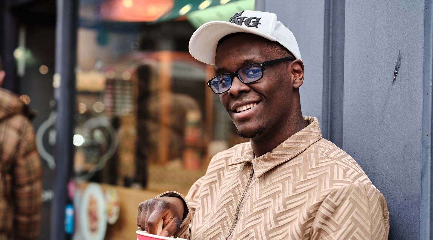 City student holding coffee cup and smiling at camera