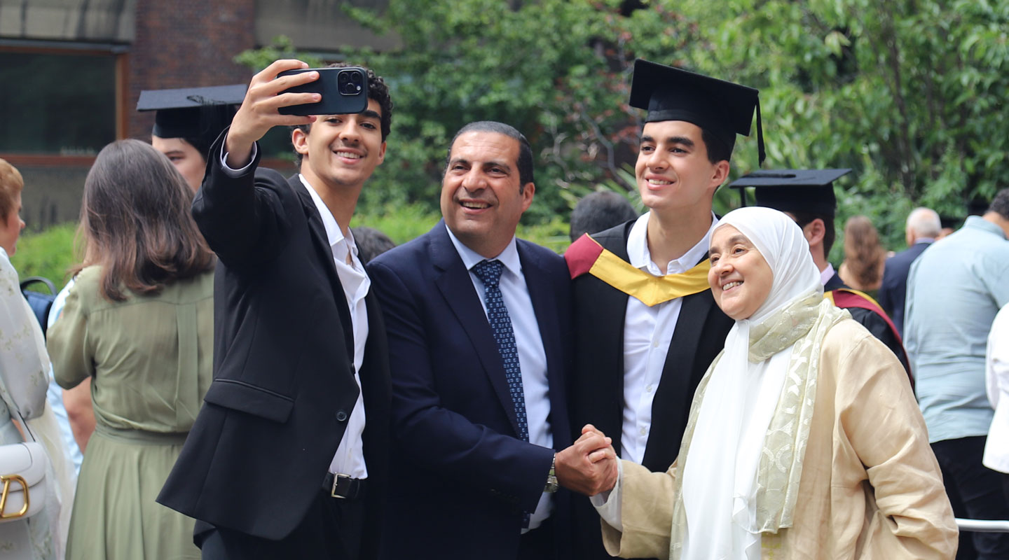 A new graduate taking a photo of themselves with their family