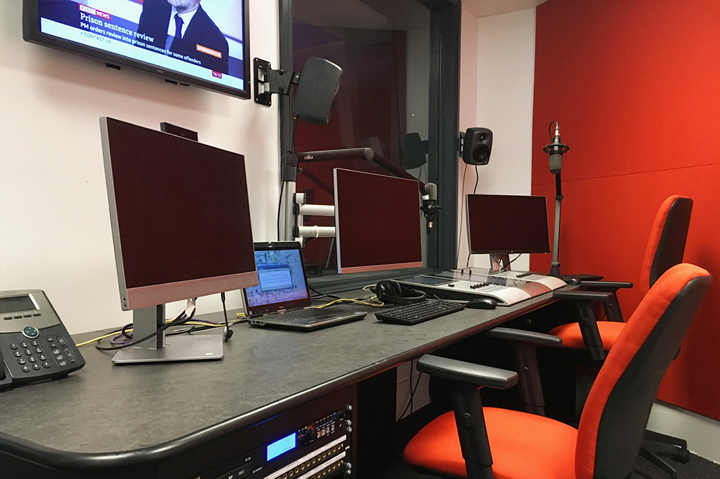 Journalism Newsroom with computers and live TV news feed