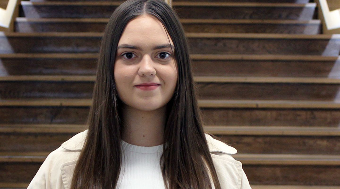 Headshot of Lana in front of the main university staircase.