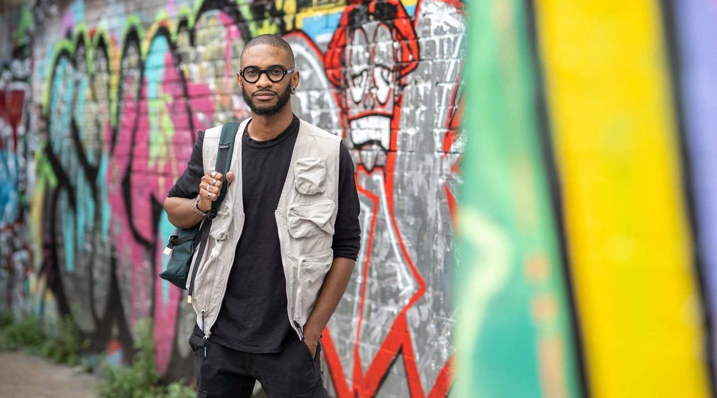 A City alumnus in a street with murales