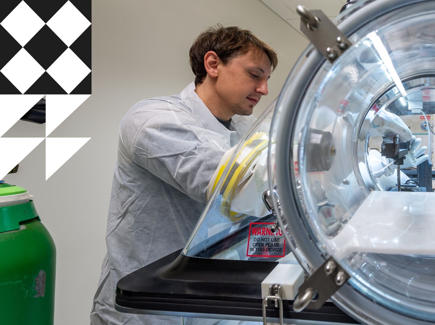 Male researcher wearing a white lab coat and gloves working on optic sensor monitoring system.