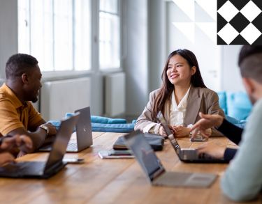 Female student smiling surround by laptops on a desk