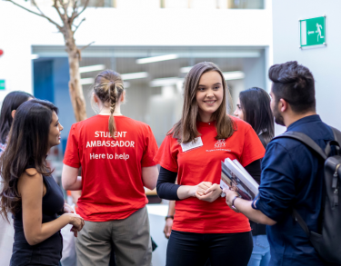 A student ambassador and staff member helping a student during an event