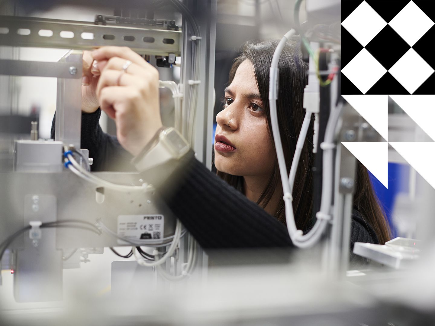 Female student adjusting equipment in the Industry 4.0 lab.
