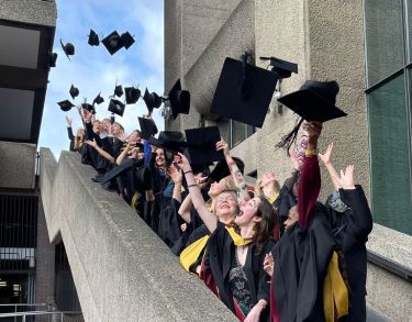 New graduates throwing their mortarboards into the air in celebration