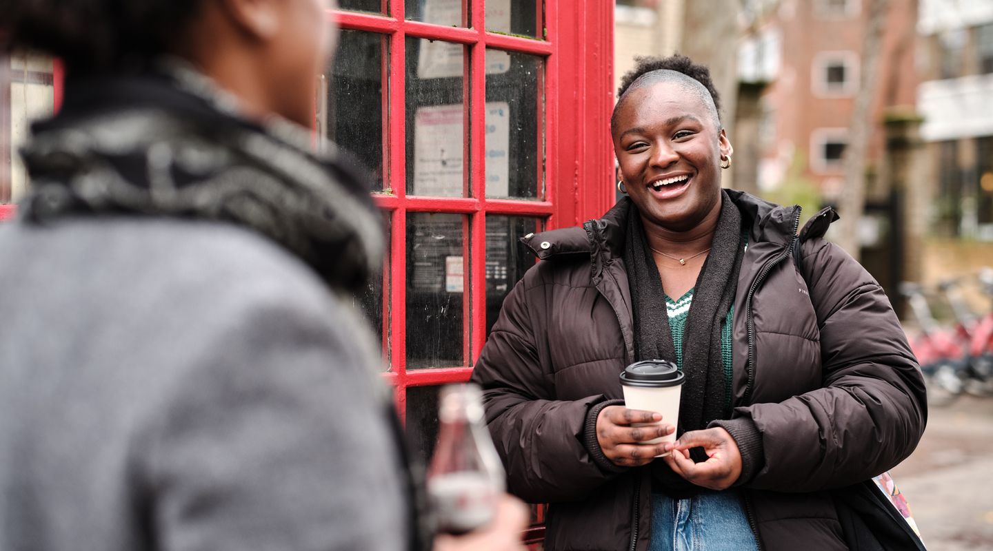 City student laughing and chatting next to red phone box