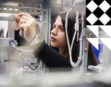 Female student adjusting equipment in the Industry 4.0 lab.