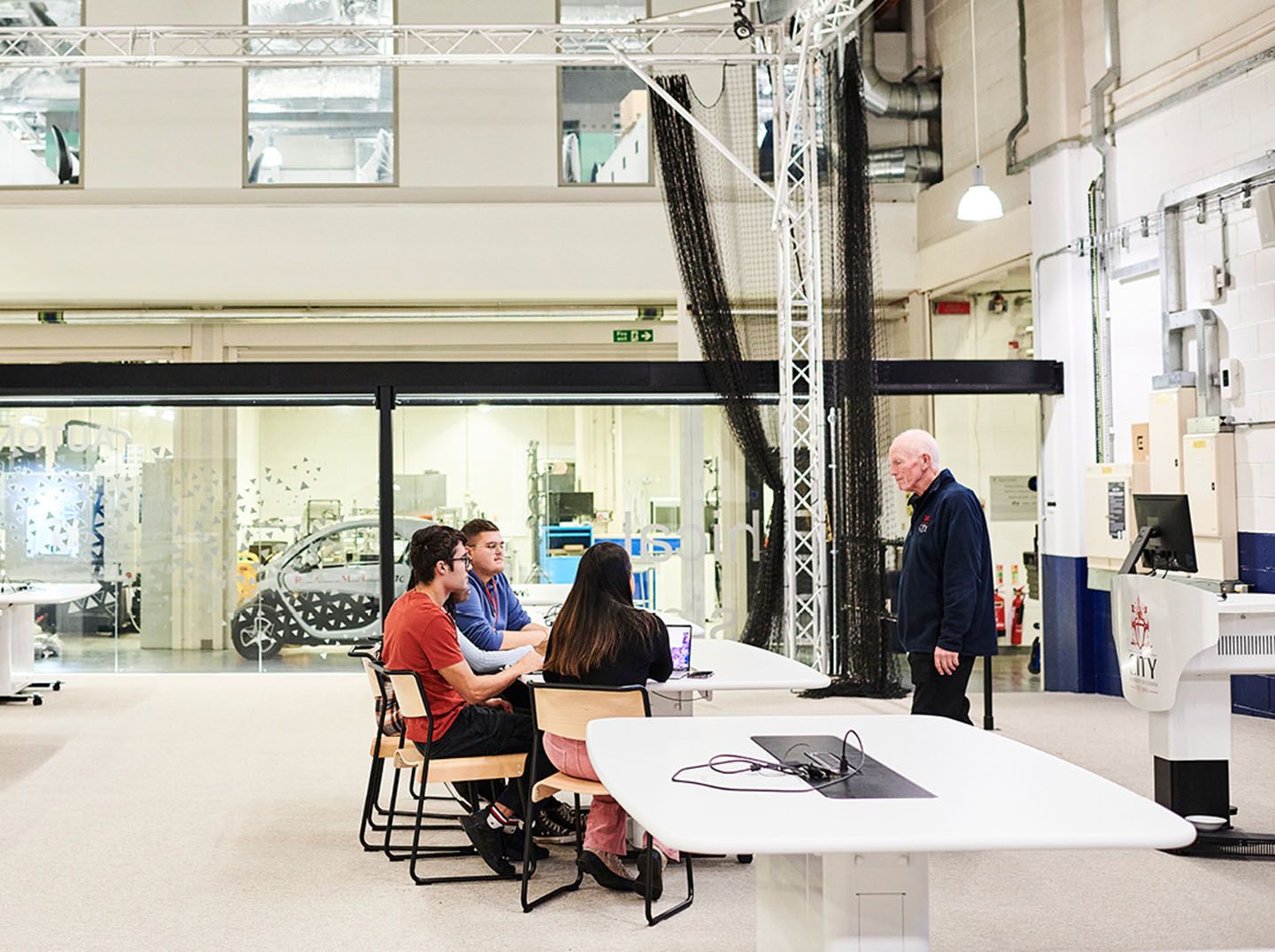 Photo of a group of students speaking to staff member in the Engineering labs