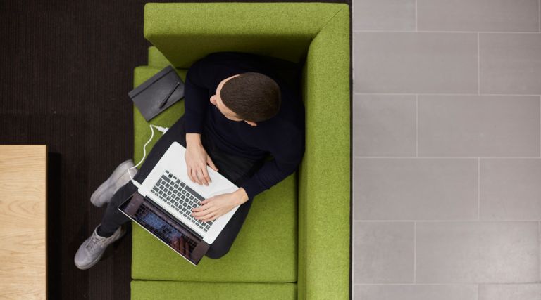 Student sitting on a green sofa with a laptop. Credit: Laurie Griffith 