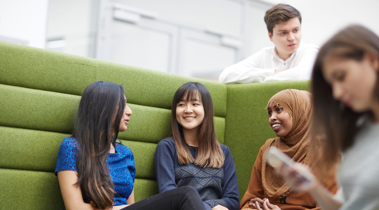Students socialising in a green booth inside the university.
