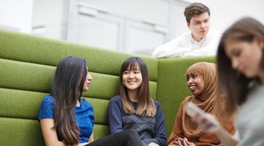 Students socialising in a green booth inside the university.