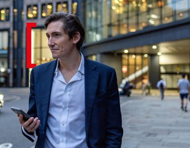 Person standing in front of a building with a phone in his hand